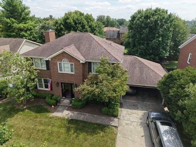 Before: two-story brick colonial with a weathered brown shingle roof, seen from the front