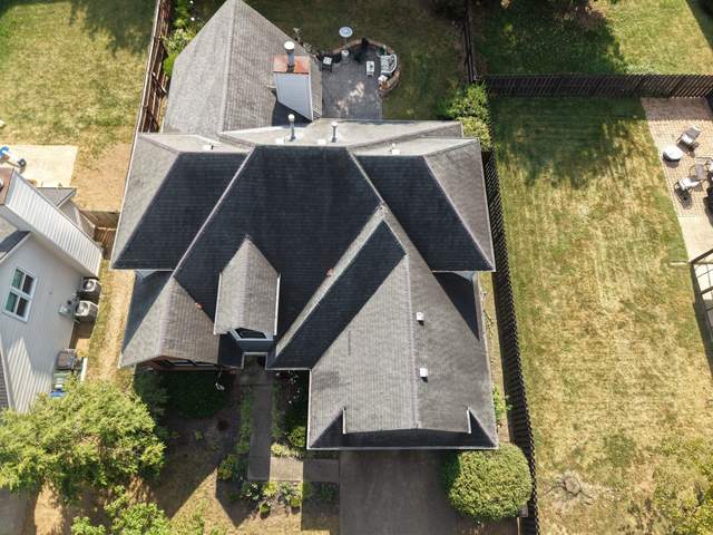 Before: top-down drone view of a brick and vinyl home with a dormer and its old roof