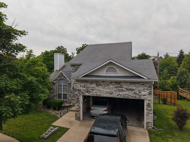 Before: painted-brick and stone home with its old roof, seen from above the front
